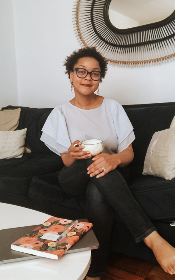 Jane Jones, PhD holding a cup of tea on the couch